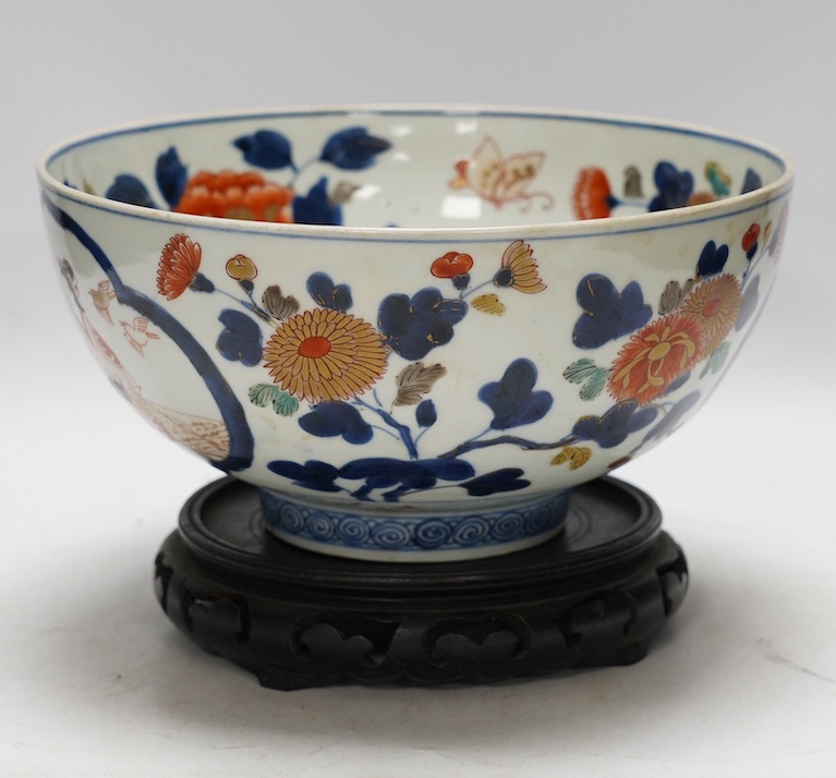 A Japanese Arita polychrome bowl, c.1700, diameter 24.5cm, height 12.5cm, on a carved hardwood stand. Condition - large overglazed open firing crack to foot, otherwise good